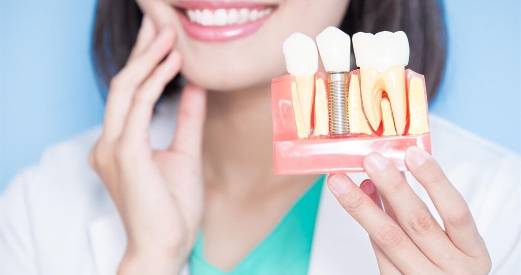 woman dentist take implant tooth and touch tooth on the blue background